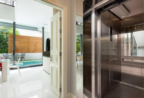 eine Glastür, die in eine Küche mit einem Pool führt in der Unterkunft Modern Luxury Poolhaus with Lift in Klong Toi