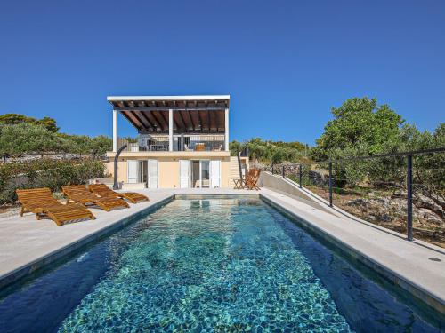 a swimming pool with chairs and a house at Holiday Home Sova by Interhome in Nečujam