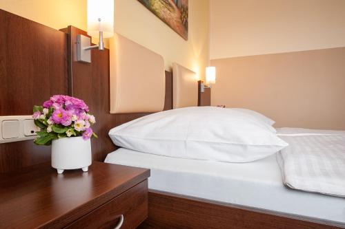 a bedroom with a bed and a vase of flowers on a table at LuCA Hotel in Bodenmais