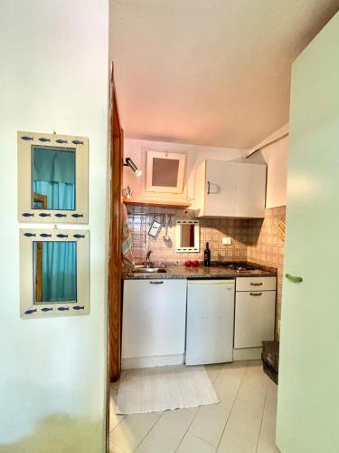 a kitchen with white cabinets and a white refrigerator at Casa Aaron - Monolocale con veranda sul mare in Stintino