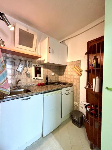 a kitchen with white cabinets and a sink at Casa Aaron - Monolocale con veranda sul mare in Stintino