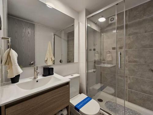 Un baño con ducha, inodoro y lavabo. en Modernos departamentos, en Santiago