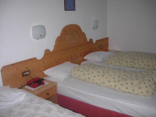 a bedroom with two beds and a wooden headboard at Hotel Albe in Rocca Pietore