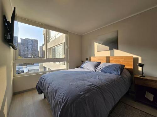 Un dormitorio con una cama grande con una ventana grande. en Modernos departamentos, en Santiago