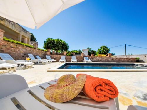 Un par de sombreros de paja sobre una mesa cerca de una piscina. en Holiday Home Villa Meri by Interhome, en Benkovac