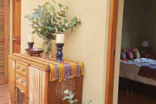 a table with two candles and a vase with flowers on it at Charming Urubamba Cusco house - Kapuliyuq in Urubamba