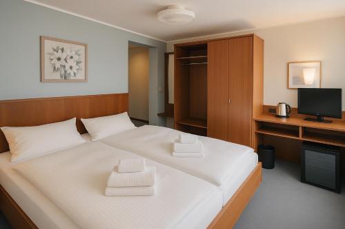 a bedroom with a large white bed with a television at Goldene Gerste in Frankfurt/Main