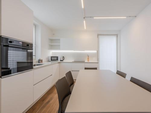 a white kitchen with a long table and chairs at Apartment Olga by Interhome in Pinzolo