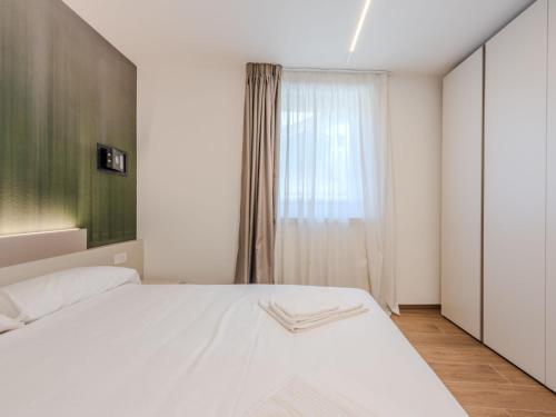 a bedroom with a white bed and a window at Apartment Olga by Interhome in Pinzolo