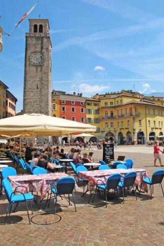 a group of tables and chairs with a clock tower at Apartment Boschetto by Interhome in Riva del Garda