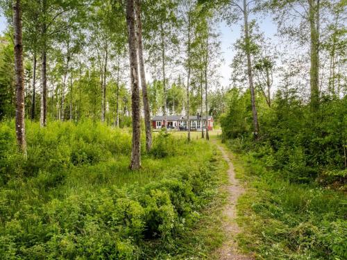a dirt road through a forest with a house in the background at Holiday Home Jönsamåla by Interhome in Ryd