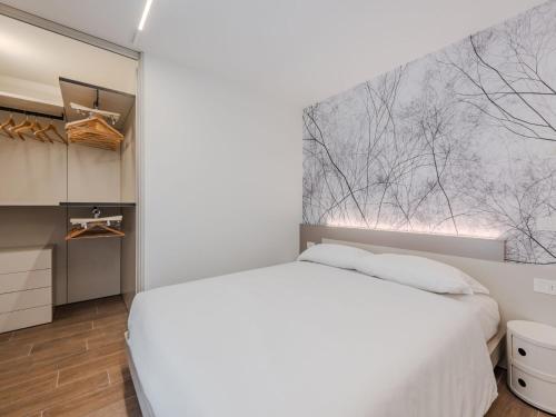 a bedroom with a white bed and a painting on the wall at Apartment Maria by Interhome in Pinzolo