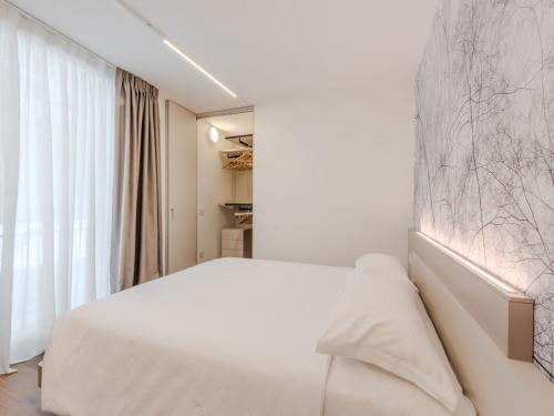 a white bedroom with a white bed and a large window at Apartment Maria by Interhome in Pinzolo