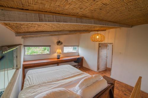 a bedroom with a bed and a desk and a window at The Sri Loft in Dalung