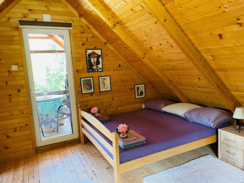 a bed in a wooden cabin with a window at Property with your own beach and pool - Whispering Waters in Krupa na Vrbasu