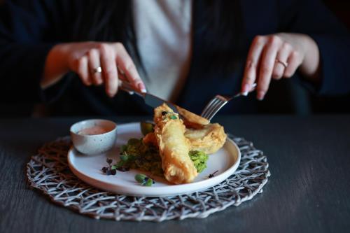 a person holding a knife and fork and a plate of food at Central Hotel Radviliškis in Radviliškis