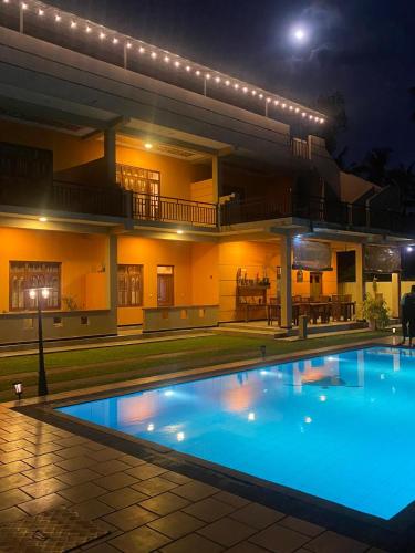 a large swimming pool in front of a house at night at Woodnest Saayoo Resort in Negombo