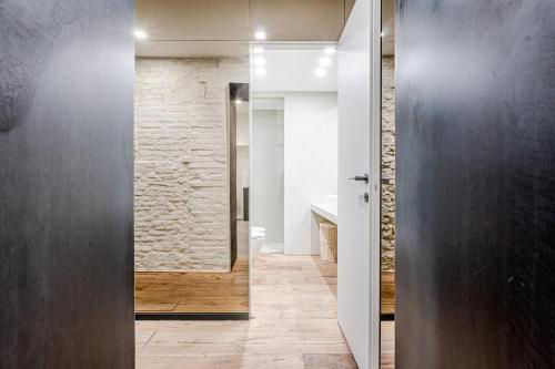 a bathroom with a door leading into a bathroom with a stone wall at Casa Sapienza - Luxury Apartment in the Centre in Siena