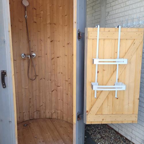 a wooden shower stall with a wooden door at Strandmuschel in Aventoft