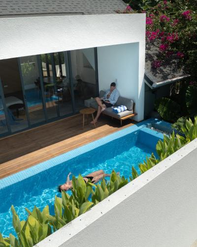 a man sitting on a couch next to a swimming pool at Villa Mia Fulhadhoo in Fulhadhoo
