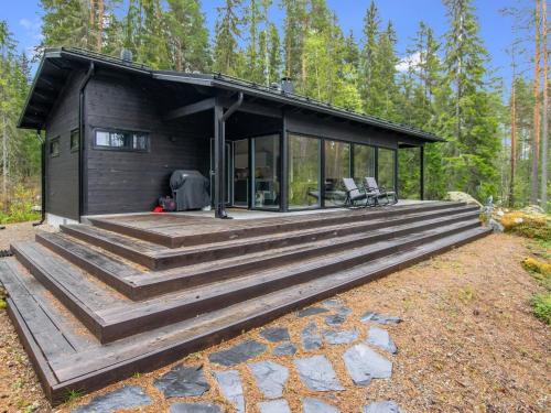 a cabin in the woods with a large wooden deck at Holiday Home Sarppala by Interhome in Putkijärvi