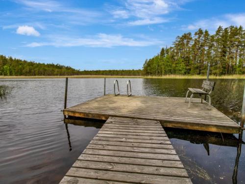 a wooden dock with a chair sitting on top of a lake at Holiday Home Paloniemi by Interhome in Savitaipale