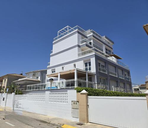 Un edificio blanco con una valla delante. en Oliva Moon, en Oliva