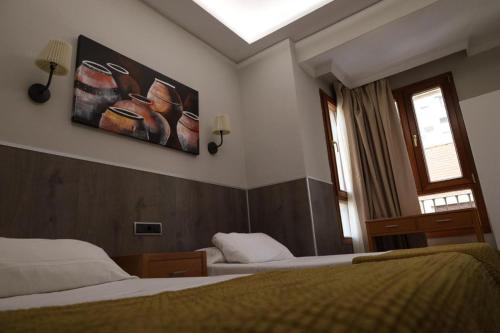 a bedroom with two beds and a painting on the wall at Hostal Victoria in Málaga