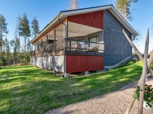 uma casa com uma porta vermelha e uma varanda em Holiday Home Järven idylli by Interhome em Virmutjoki