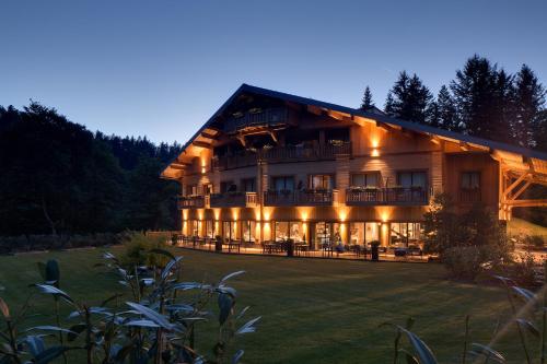 a large wooden building with lights on it at Domaine de Montagne - Hôtel Chalet Frère Joseph in Ventron
