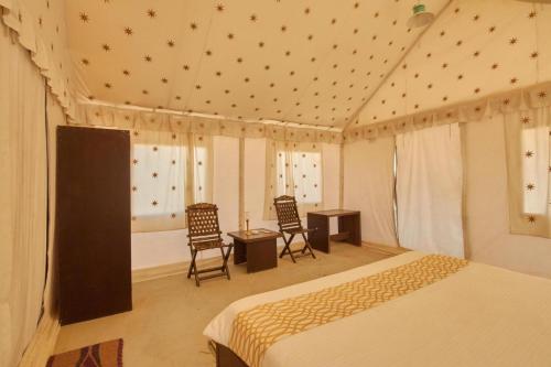 a bedroom with a bed and two chairs and a table at Savi Camps Jaisalmer in Sām