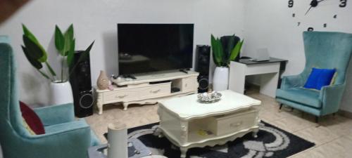 a living room with two chairs and a flat screen tv at Spacious One bedroom serviced apartment with Wifi Smart TV Air conditioning kitchen and other facilities in a cozy living space in Lagos