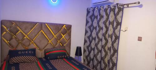 a bed with a head board and a curtain at Spacious One bedroom serviced apartment with Wifi Smart TV Air conditioning kitchen and other facilities in a cozy living space in Lagos