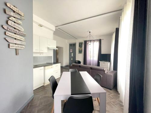 a kitchen and living room with a table and chairs at Appartement dans un parc arboré privé in Bégard