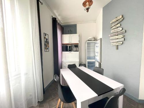 a kitchen with a white table and a refrigerator at Appartement dans un parc arboré privé in Bégard