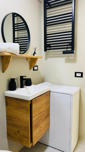 a bathroom with a sink and a washing machine at LAC Holiday Apartment in Calceranica al Lago