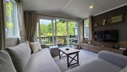 a living room with a couch and a tv at 57 The Meadows FallBarrow Park in Bowness-on-Windermere