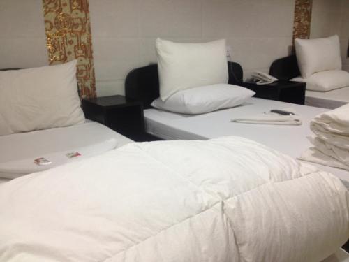 2 camas en una habitación con sábanas y almohadas blancas en Manhattan Guesthouse, en Hong Kong