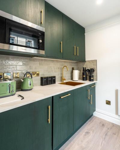 a kitchen with green cabinets and a sink at No 5 Rose Inn Street - Room 1 in Kilkenny