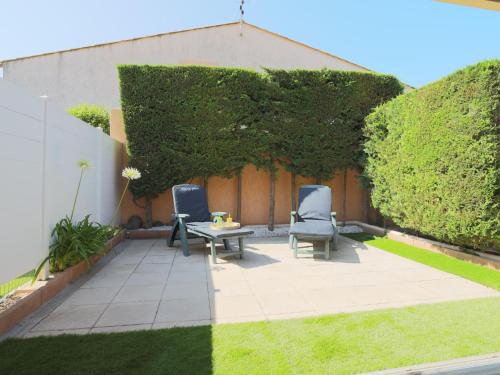 a patio with two chairs and a table in a yard at Holiday Home Hacienda Beach II-7 by Interhome in Agde