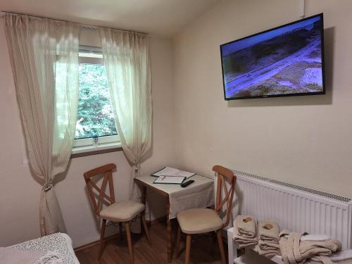 a room with a table and chairs and a television on the wall at Haus Hoogendam in Leoben