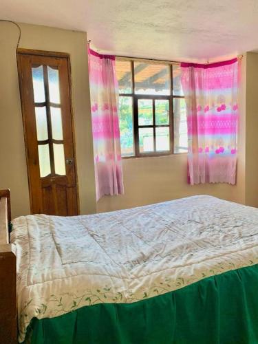 a bedroom with a bed and two windows at Hostal Inty Kucha in Otavalo