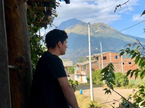 a man looking out of a window at a mountain at Hostal Inty Kucha in Otavalo