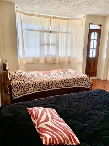 a bedroom with two beds and a window at Hostal Inty Kucha in Otavalo