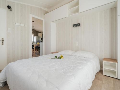 a white bedroom with a large white bed with flowers on it at Chalet Le Bois d'Amour 2-2 by Interhome in Dinard