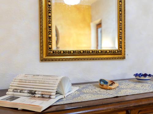 a stack of books on a table with a mirror at Holiday Home Lu Nibbaru di Portobello by Interhome in Aglientu