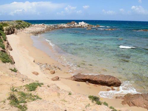 a sandy beach with rocks and the ocean at Holiday Home Lu Nibbaru di Portobello by Interhome in Aglientu