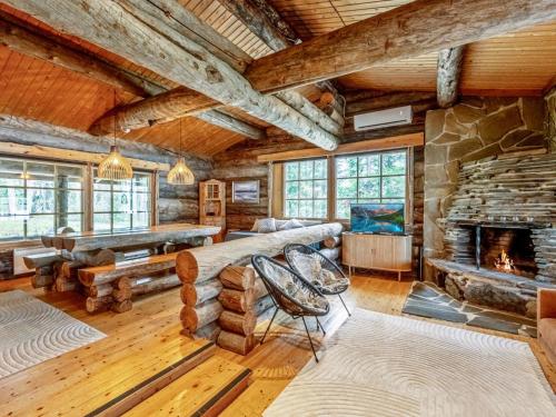 a log cabin living room with a stone fireplace at Holiday Home Lumikenttien kutsu by Interhome in Kuusamo