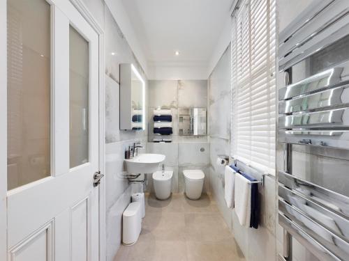 a white bathroom with two toilets and a sink at No 3 at Upton Cross House, Chester in Backford