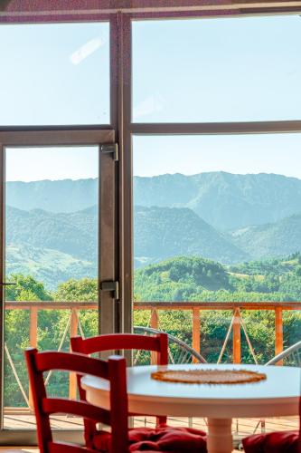 a table and chairs on a balcony with a view of mountains at Suspended Tiny House in Drumu Carului